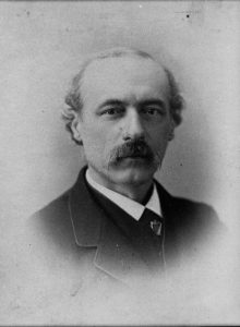 James Redpath, ca. Jan. 1, 1870 - Dec. 31, 1890. Photographer: Packard. Image courtesy of Kansas Historical Society. Head and shoulders portrait. Redpath is wearing a black suit, black vest and tie, and white collared shirt.