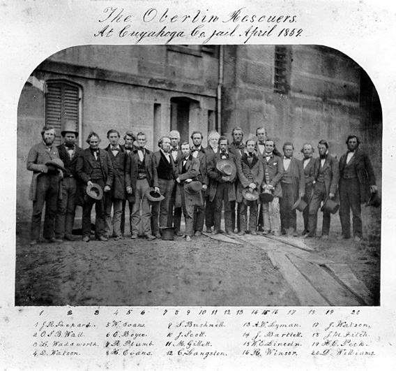 Black and white image of men standing in a group for photograph