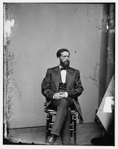 Photograph of John Mercer Langston seated on a stool